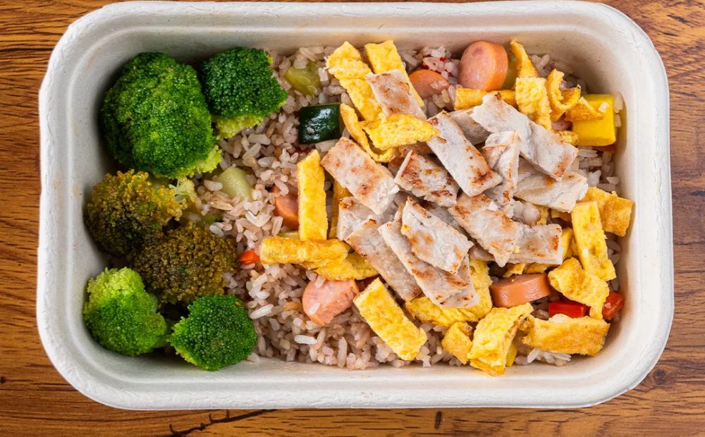 Yakimeshi de cerdo con arroz, tortilla en tiras y brócoli en el envase del menú diario de Manzana Verde