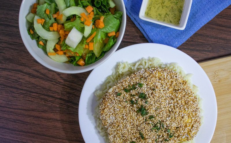 Pechuga empanizada con amaranto sobre arroz, con ensalada de lechuga, pepino y zanahoria de Manzana Verde