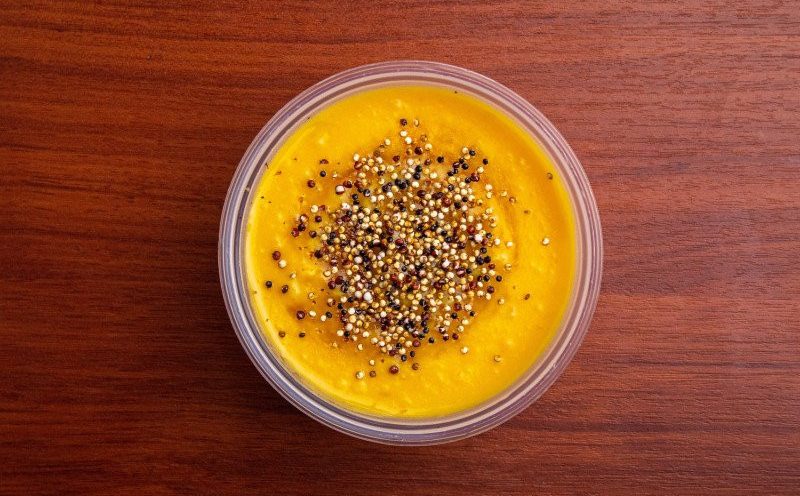 Puré dulce de camote con quinoa inflada en un envase transparente sobre una mesa de madera